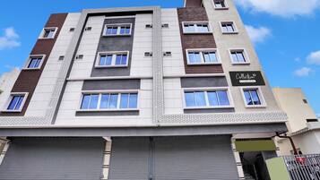 Un edificio de varios pisos con un diseño arquitectónico moderno, que presenta una combinación de fachadas de ladrillo y enlucido, ventanas grandes y un letrero de empresa.