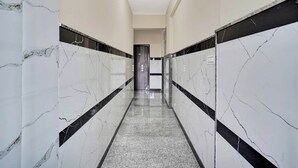 A corridor with white marble walls and black borders, leading to a door. - Collection O K R Puram (Bangalore)