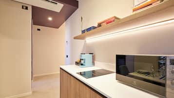 Una cocina moderna con microondas integrado, cafetera y isla con encimera de vidrio.