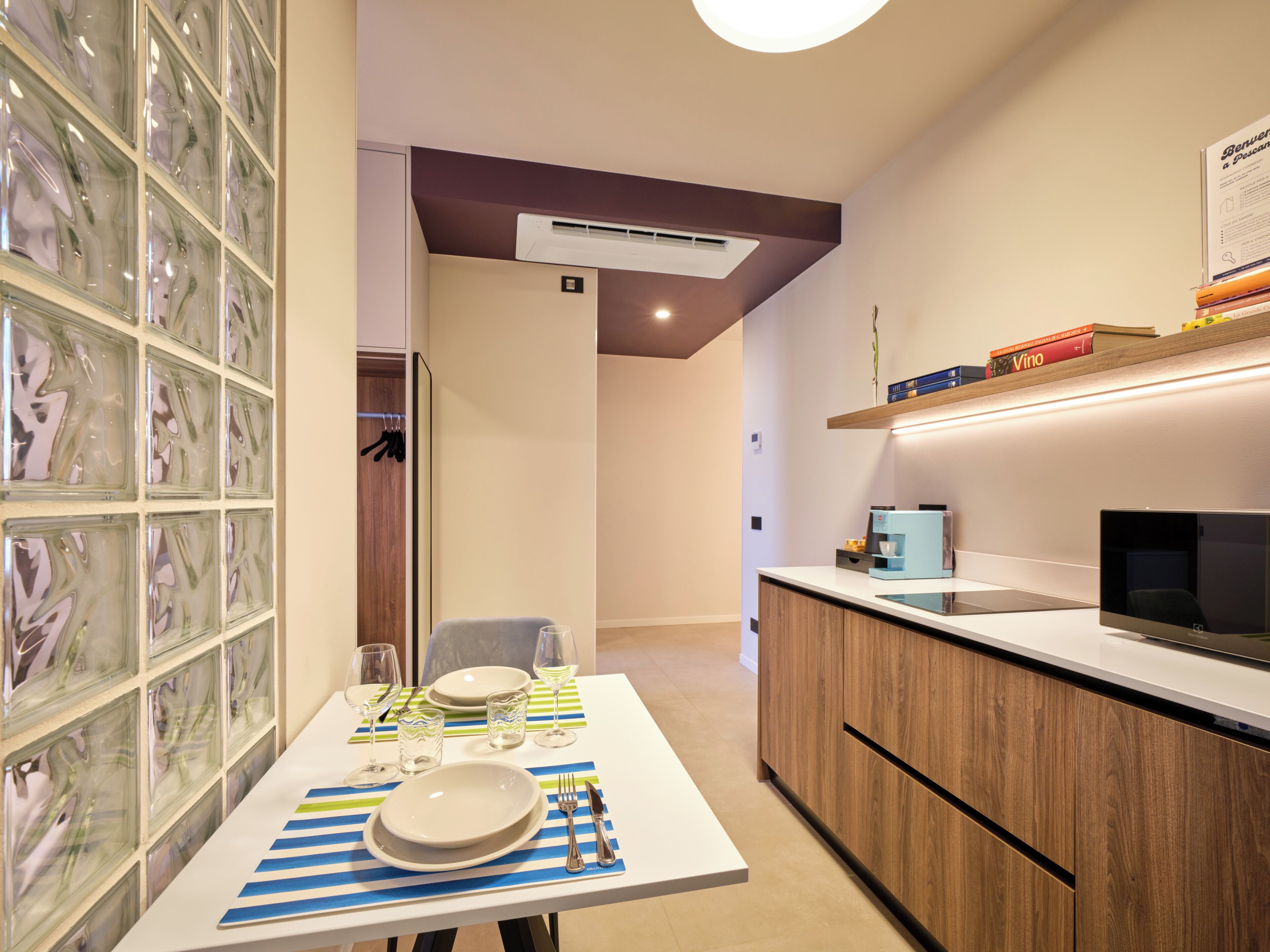 A modern kitchen with a built-in TV, a coffee machine, and a dining area with a table set for two.