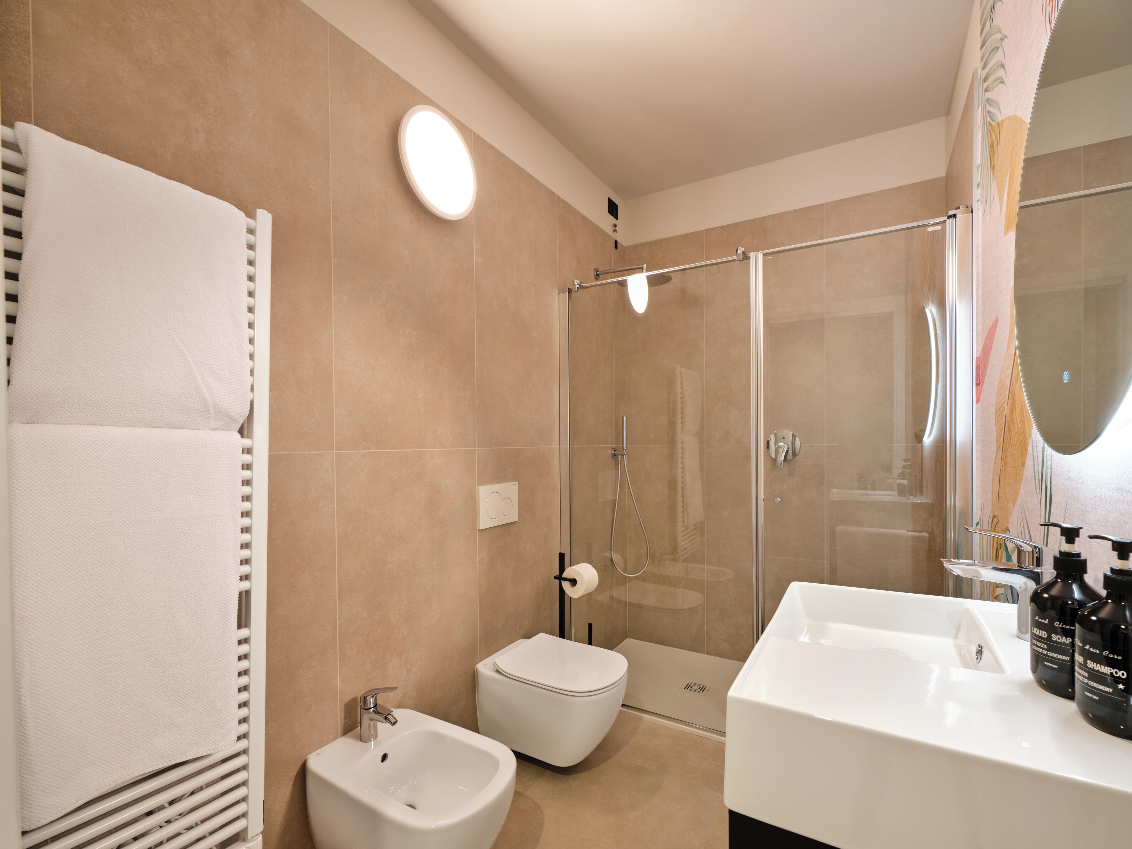 Un baño moderno con ducha, bidé y un espejo grande.