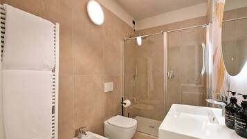 Un baño moderno con ducha, bidé y un espejo grande.