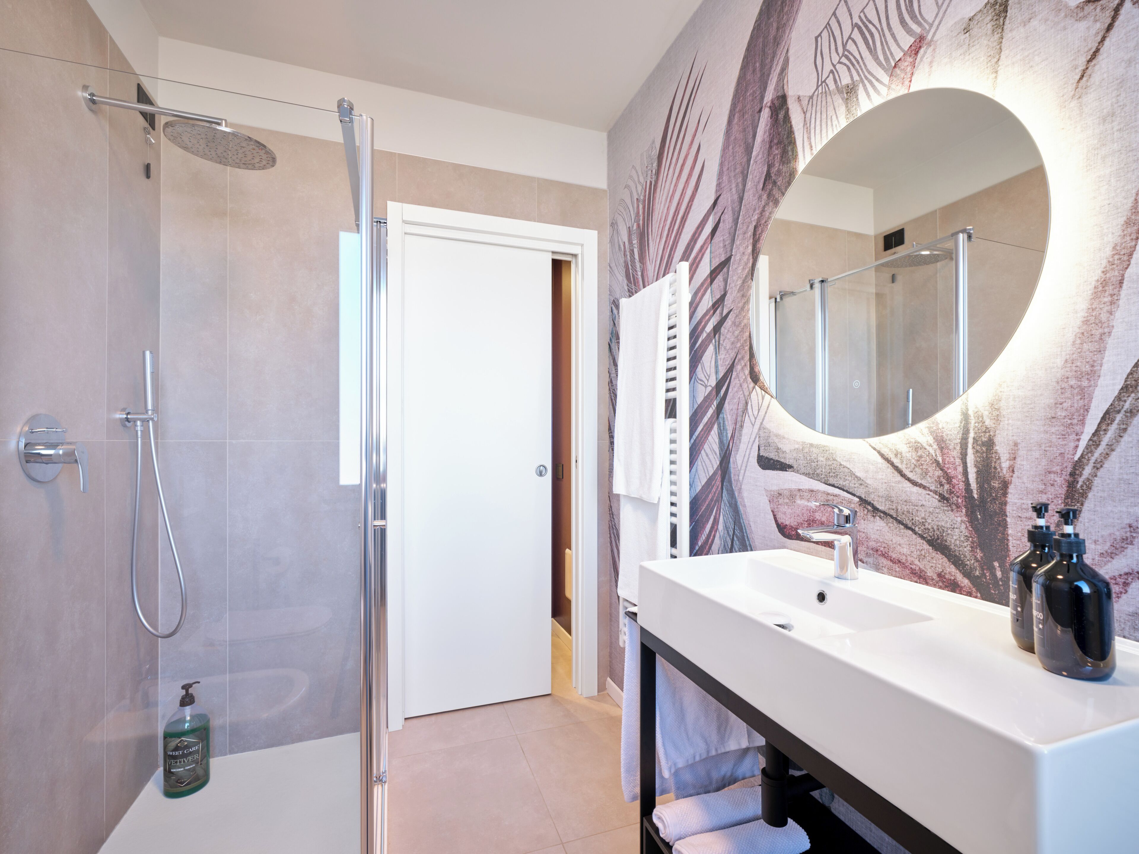 Un baño moderno con ducha, lavamanos y espejo.