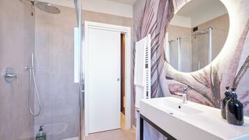 Un baño moderno con ducha, lavamanos y espejo.