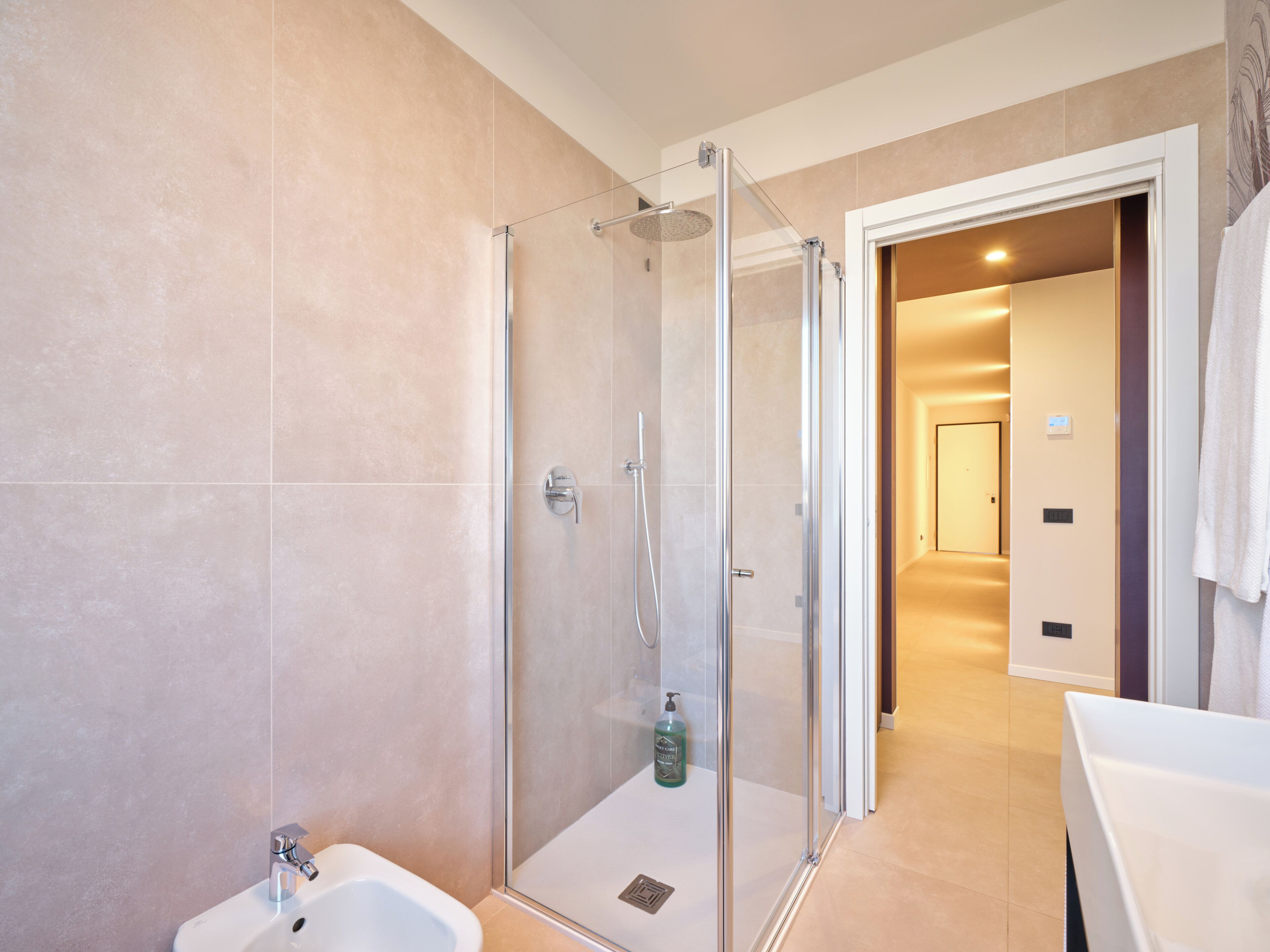 A modern bathroom with a glass-enclosed shower, a sink, and a mirror.