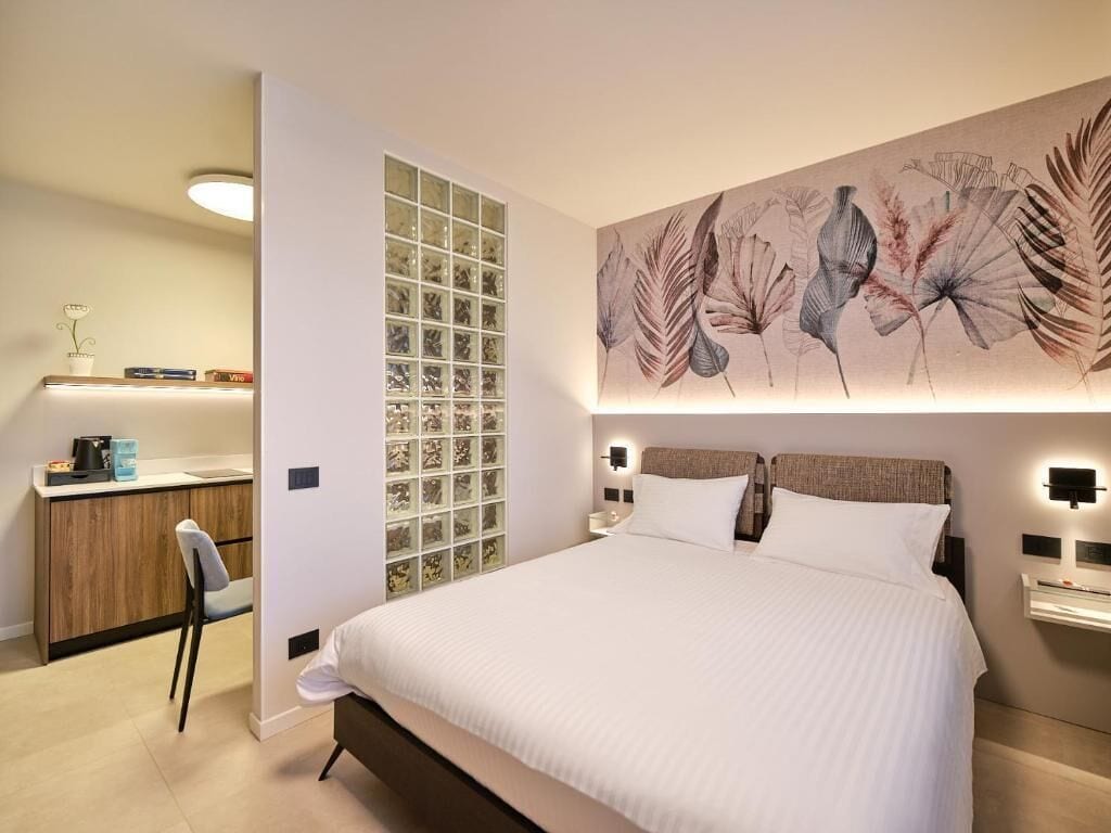 Un dormitorio moderno con una cama grande, mesitas de noche, un escritorio y un panel decorativo en la pared.
