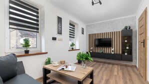 Un soggiorno moderno con un divano, un tavolino da caffè e una TV montata su un pannello di parete in legno.