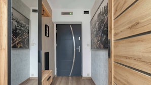 Un corridoio con una porta scura, pannelli in legno e un pavimento chiaro.