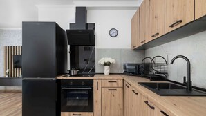 Una cucina moderna con frigorifero nero, mobili in legno, forno integrato e microonde.
