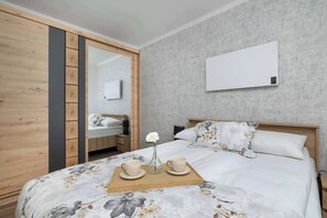 Un dormitorio con cama, mesita de noche, espejo y aire acondicionado instalado en la pared.