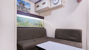 A room with a bench, a table, a clock, and a window with a view of fish.