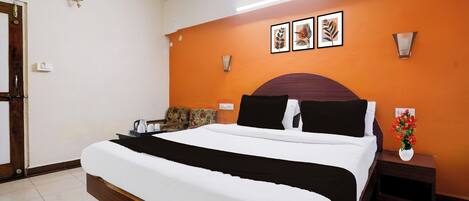 A hotel room with a bed, a nightstand, a vase with flowers, and wall art.