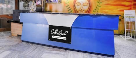 A reception desk with a sign indicating a reception area, a wall with a Buddha mural, and a sign stating 'Collection Company-Serviced'.