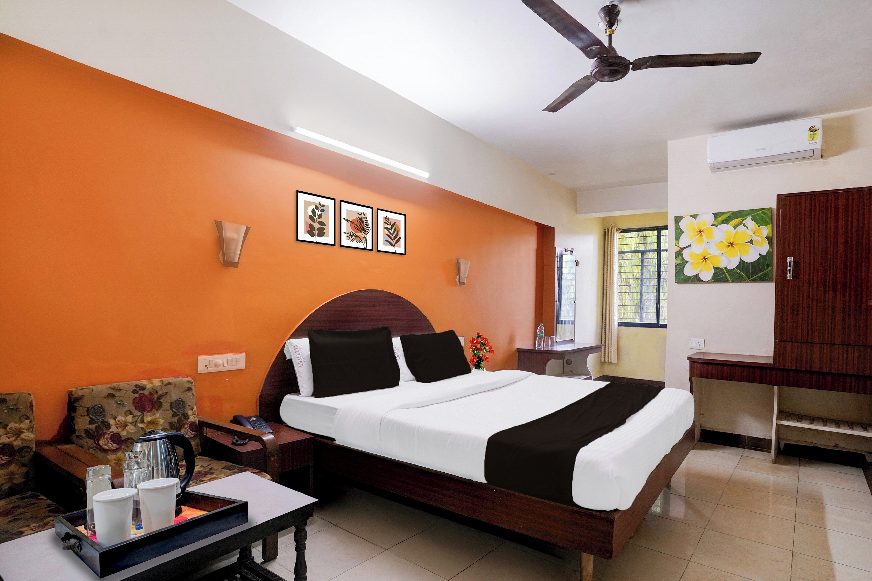 A hotel room with a bed, bedside table, and a desk.