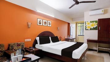 A hotel room with a bed, bedside table, and a desk.