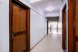 Un pasillo con una puerta de madera con la etiqueta '215', que conduce a una habitación con ventana y puerta.