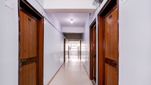 A corridor with wooden doors, white walls, and a tiled floor.