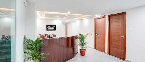 A reception area with a wooden reception desk, potted plants, and a sign indicating company services.