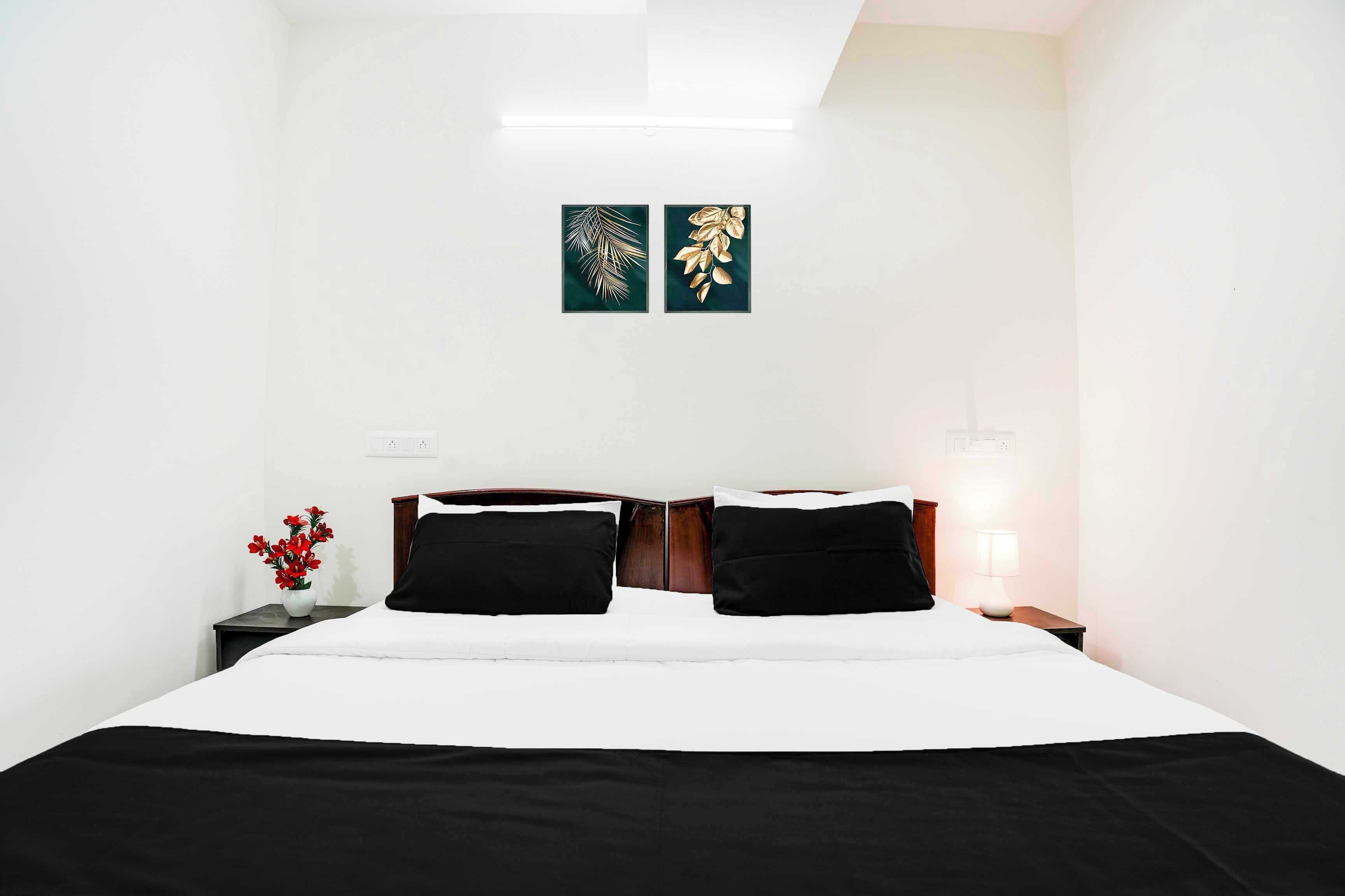 A hotel room with a bed, two nightstands, a lamp, and two wall art pieces.