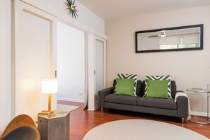 A living room with a sofa, a lamp, a round rug, and a side table. - Bright Homely 2BR in St Kilda East w Parking (Saint Kilda East)