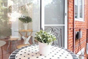 A round table with a patterned tablecloth, a potted plant, and a glass door with reflections. - Bright Homely 2BR in St Kilda East w Parking (Saint Kilda East)
