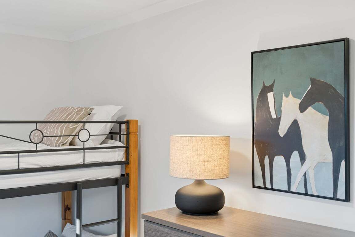 En køjeseng med en lampe og et billede på væggen.
