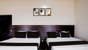 Habitación de hotel con dos camas, un cabecero de madera oscura y tres cuadros enmarcados en la pared.