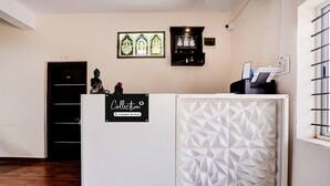 Una recepción con un cartel que indica servicio de empresa, una estatua y arte religioso enmarcados en la pared.