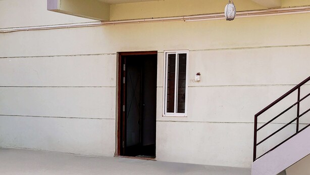 Una habitación con una puerta, un ventanal pequeño y una escalera.