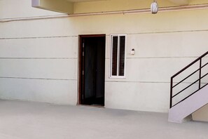 Una habitación con una puerta, un ventanal pequeño y una escalera.