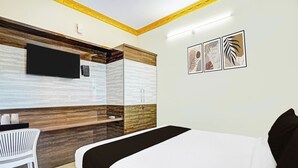 A hotel room with a bed, a desk, a flat-screen TV mounted on the wall, and a set of framed artwork. - Collection O KR Puram Ayyappa Nagar (Bengaluru)