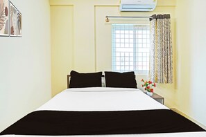 A hotel room with a bed, a window with a curtain, and an air conditioning unit. - Collection O KR Puram Ayyappa Nagar (Bengaluru)