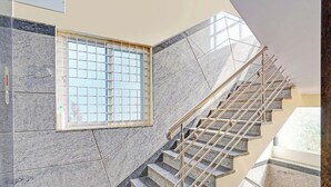 A staircase with metal handrails, a window with a grid pattern, and a tiled wall. - Collection O KR Puram Ayyappa Nagar (Bengaluru)