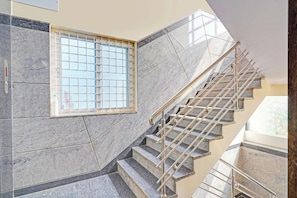 Eine Treppe mit Metallgeländern, ein Fenster mit Gitterstruktur und eine geflieste Wand.