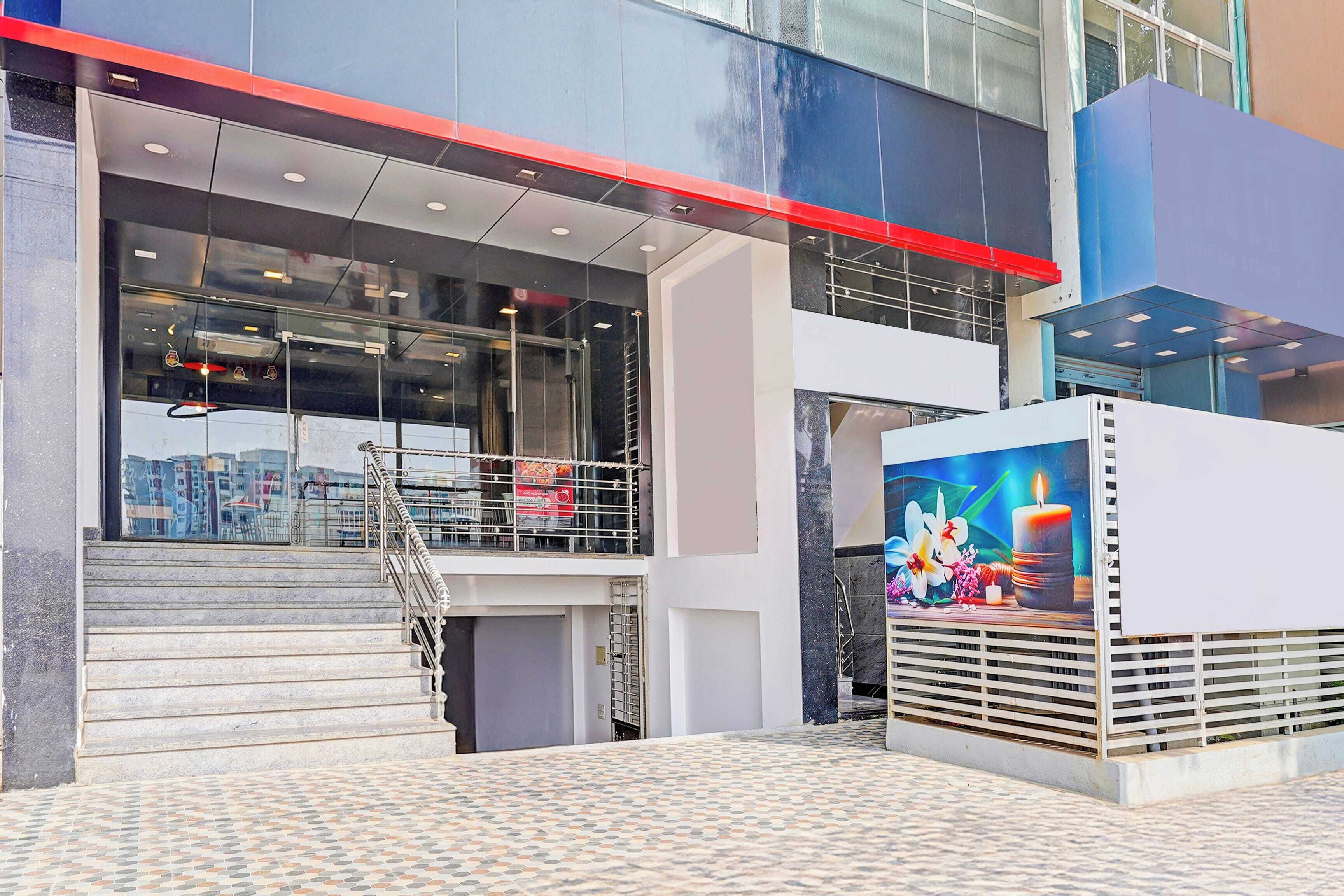 A modern building with a glass facade, a staircase leading to a lower level, and a mural on the exterior wall.