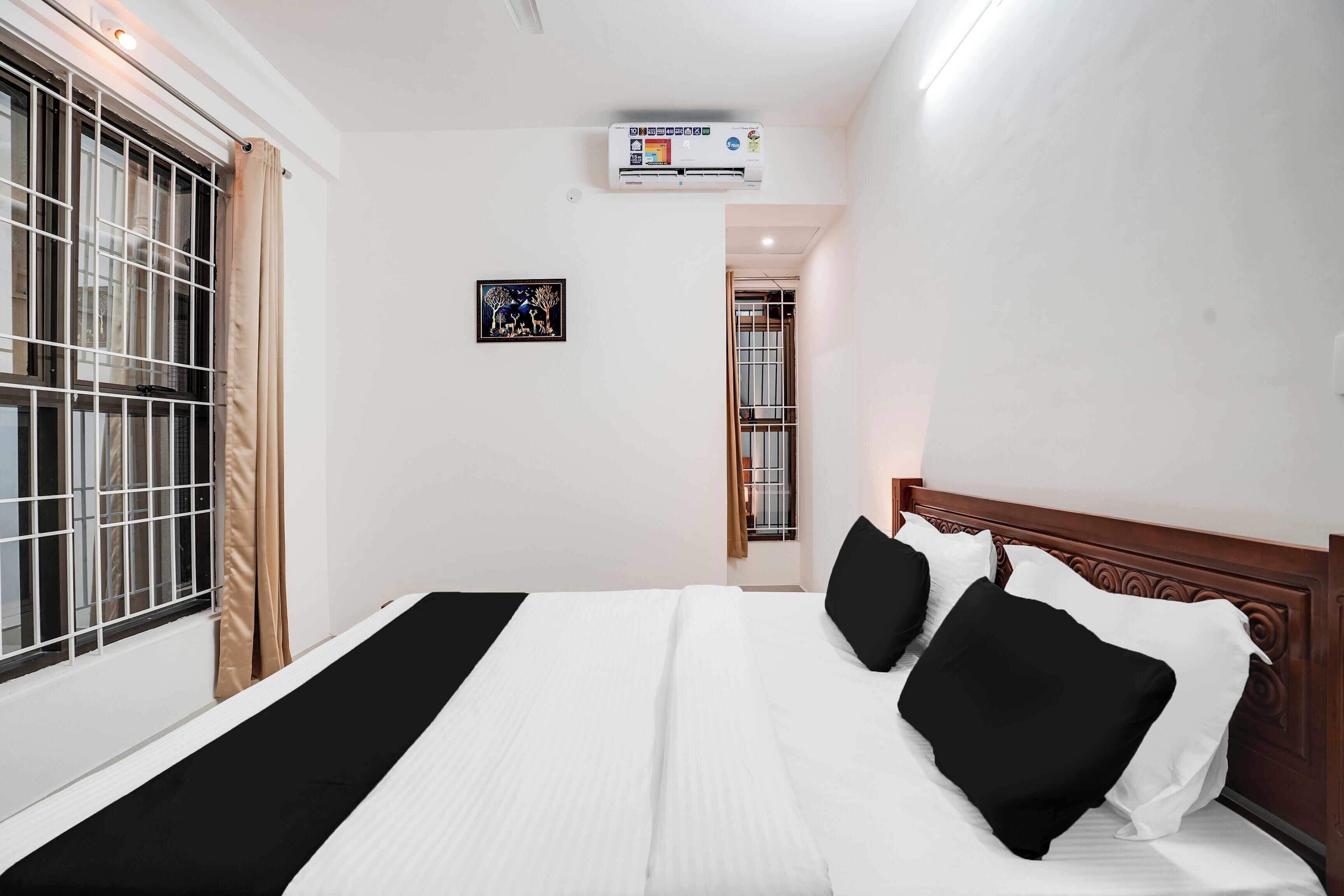 Habitación de hotel con cama, ventana con barrotes, equipo de aire acondicionado y un cuadro en la pared.