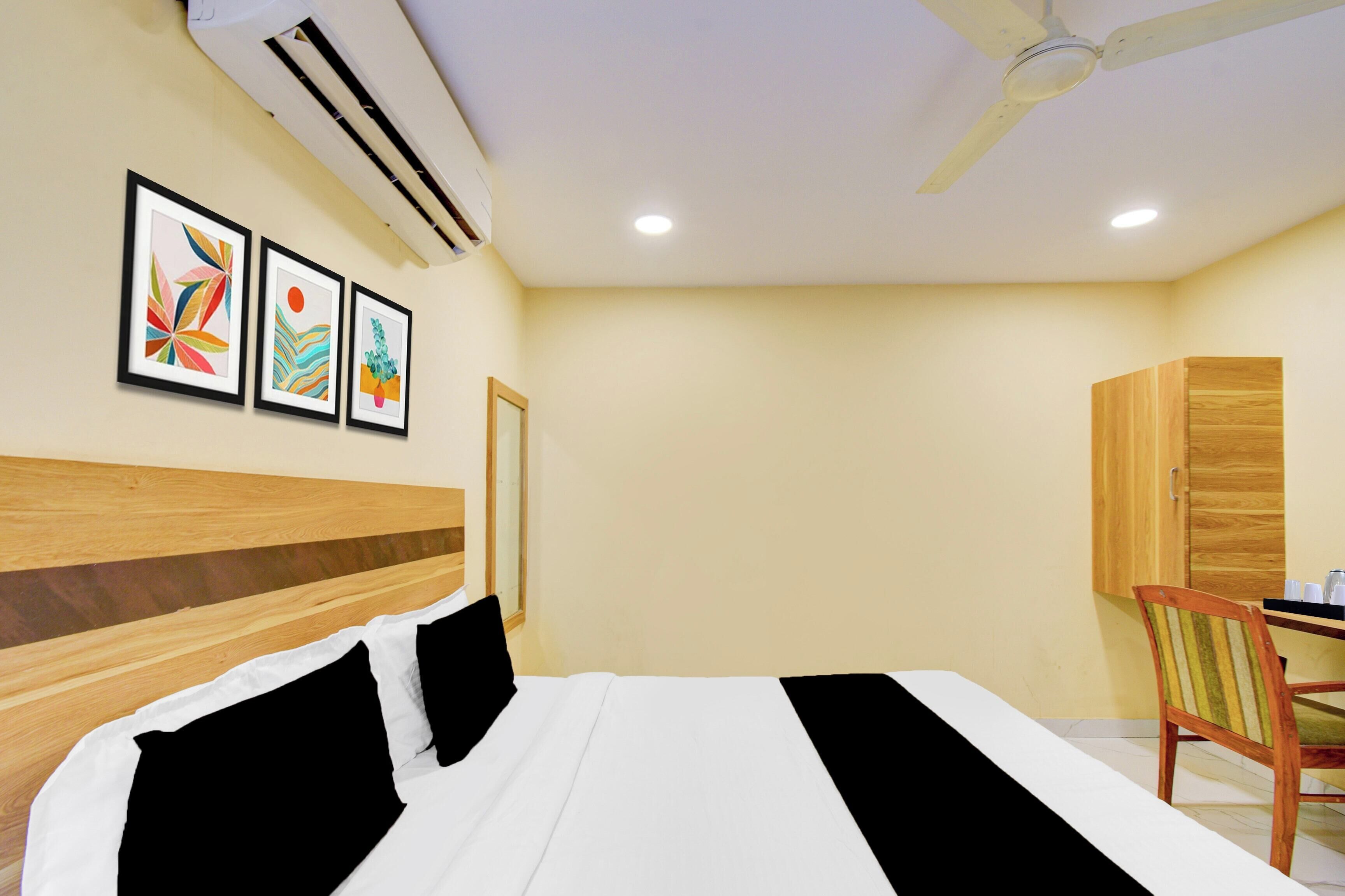 Habitación de hotel con cama, escritorio y silla. Tres cuadros enmarcados decoran la pared.