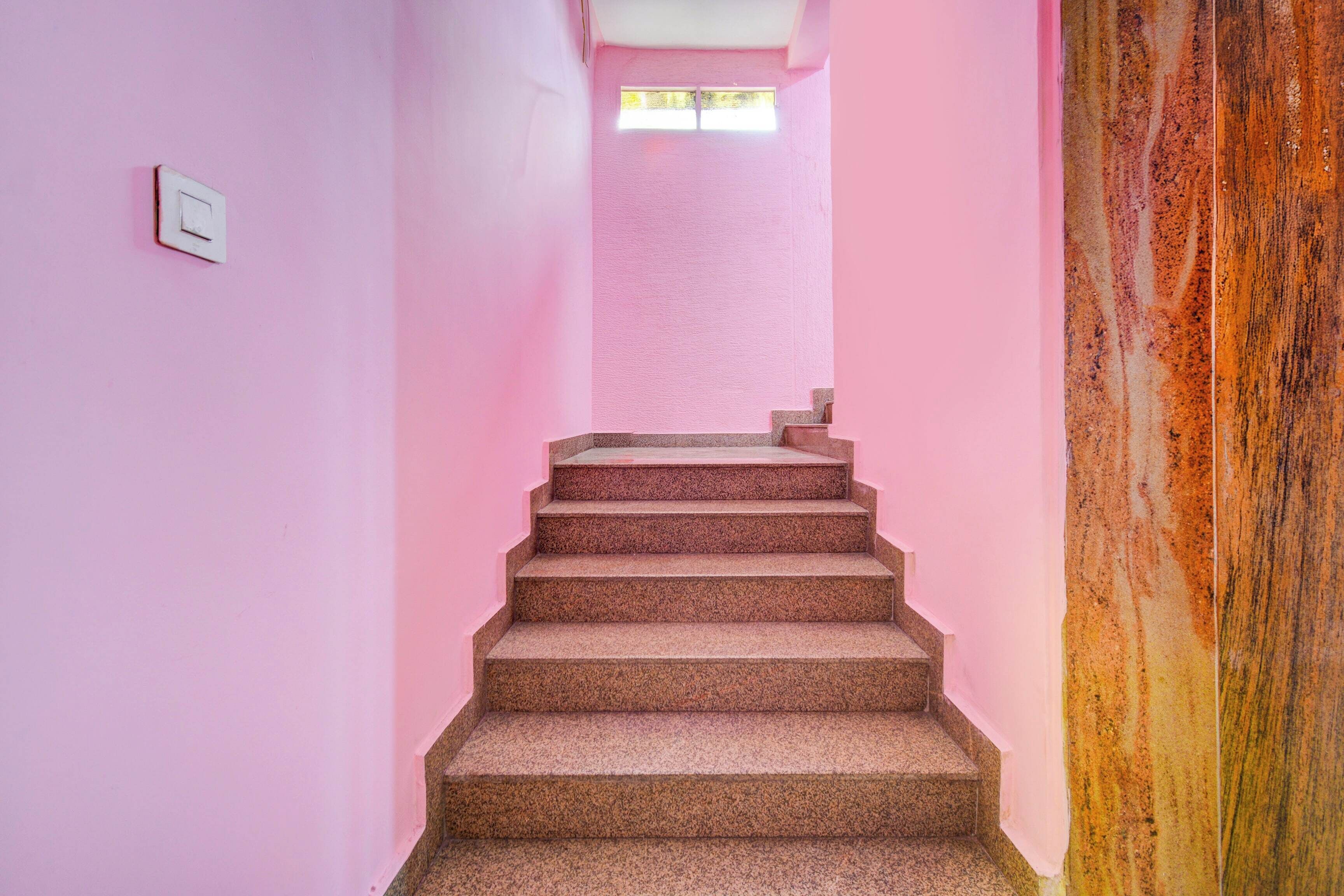 Eine Treppe mit rosafarbenen Wänden und einem Fenster oben.