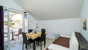 A compact living space with a dining area, a sofa, and a balcony. - Villa Samba - Standard One-bedroom Apartment With Balcony and Sea View (Zupa dubrovacka)
