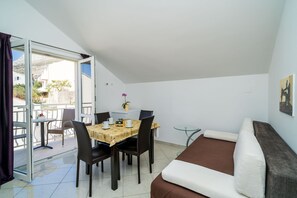 A compact living space with a dining area, a sofa, and a balcony. - Villa Samba - Standard One-bedroom Apartment With Balcony and Sea View (Zupa dubrovacka)