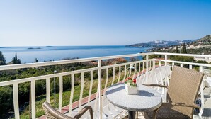 A balcony with a view of the sea, a round table, wicker chairs, and a railing. - Villa Samba - Standard One-bedroom Apartment With Balcony and Sea View (Zupa dubrovacka)