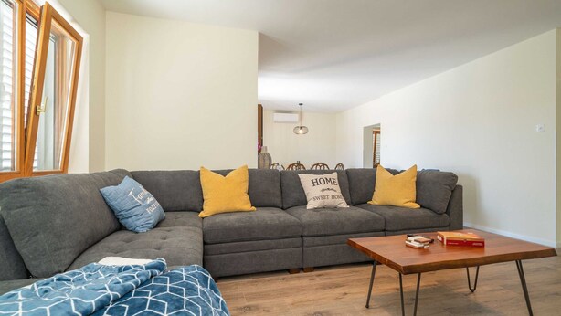 A living room with a sectional sofa, a coffee table, and a window with blinds. - Villa Pero and Jele With Terrace (Zupa dubrovacka)