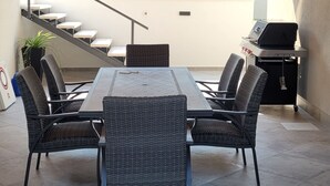 A modern outdoor dining area with a rectangular table and four wicker chairs, a staircase, and a grill station. - Villa Pero and Jele With Terrace (Zupa dubrovacka)