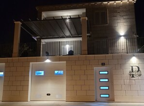 A building with a brick facade, a covered entrance, and a balcony with two people. - Villa Pero and Jele With Terrace (Zupa dubrovacka)