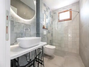 Ein Badezimmer mit einem weißen Waschbecken, einer Toilette und einer Duschkabine.