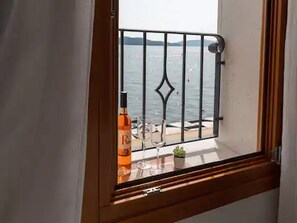 Ein Fenster mit Meerblick und einer Spirituosenflasche auf der Fensterbank.