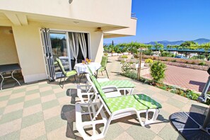 Eine Terrasse mit Tisch und Stühlen, Blick aufs Meer und ein Garten mit verschiedenen Pflanzen.