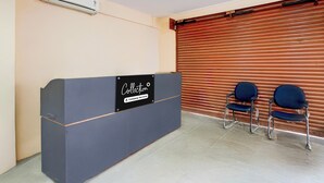 Ein Empfangsschalter mit Schild für den Abholservice, zwei Stühle, ein geschlossener Rollo und eine Klimaanlage.