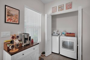 Une cuisine compacte équipée d’une machine à café, d’un grille-pain et d’un lave-linge.