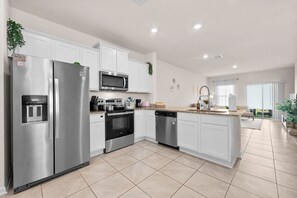 Una cocina moderna con electrodomésticos de acero inoxidable, armarios blancos y una isla grande con lavamanos.